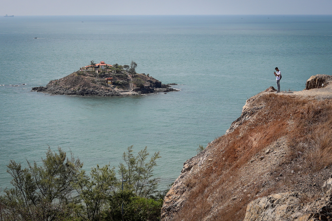 Đứng trên mô đất ven đồi, một bạn trẻ chăm chú ghi lại khung cảnh hài hòa giữa đất liền với đảo Hòn Bà giữa biển.